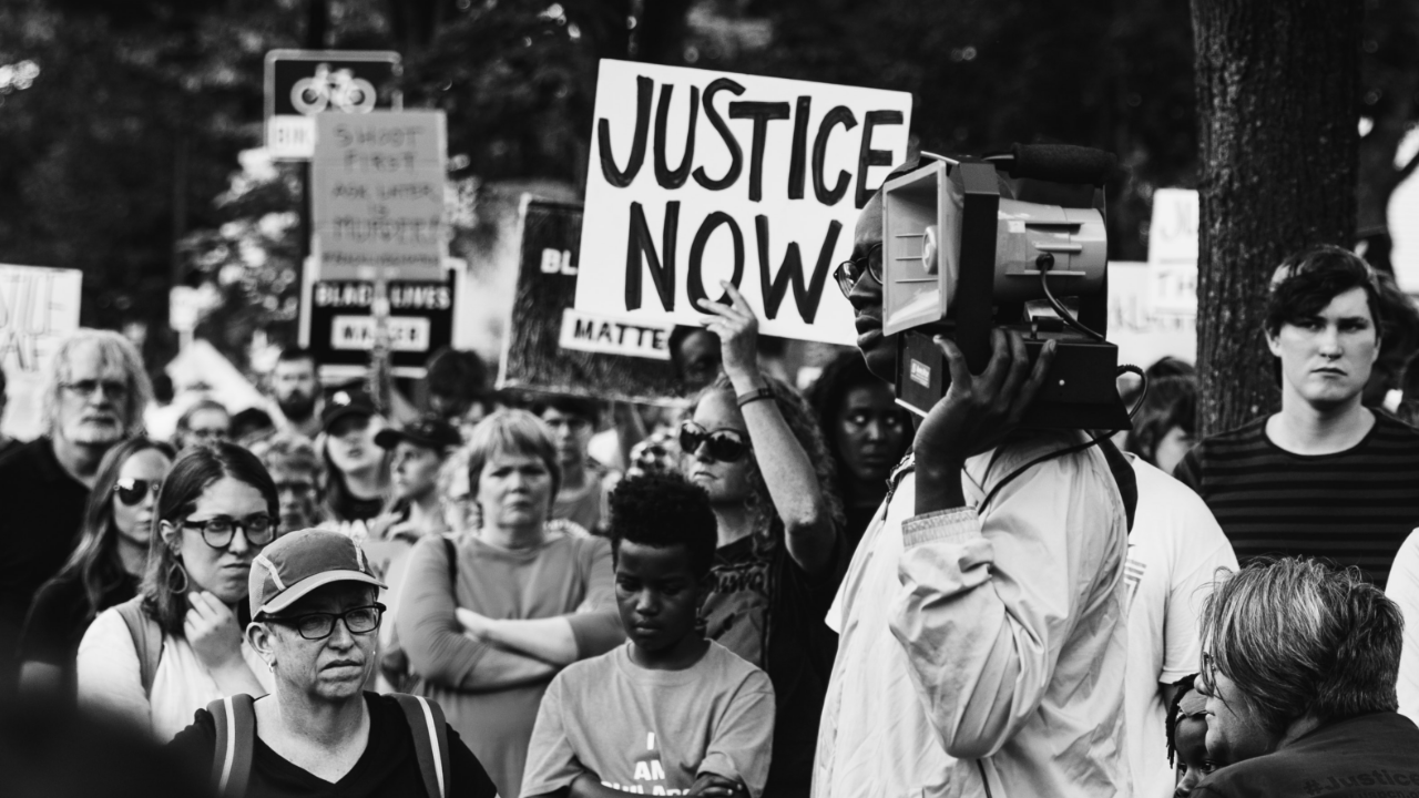 people in a rally with placards that say Justice Now